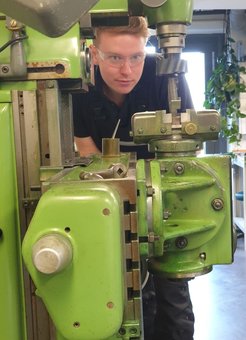 An der Fräsmaschine beim Beäugen des eingeklemmten Werkstücks. Es sitzt falsch - um sicher zu fräsen, muss Oscar es erst neu einsetzen.