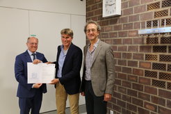 Prof. Gerhard Kramer (Vizepräsident für Forschung und Innovation, TUM) übergibt den Preis an Prof. Karsten Reuter im Beisein von Prof. Johannes Barth.
