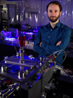 Dr. Stefan Truppe vor der kryogenen Molekularstrahlapparatur mit den zur Kühlung und Manipulation polarer Moleküle eingesetzten Lasersystemen im Hintergrund.