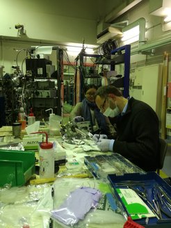 Markus Wilde and Xuefei Weng during one of the numerous repairs that were made during the research stay in Tokyo. In the background is the terminal station of the ion accelerator where the experiments took place.